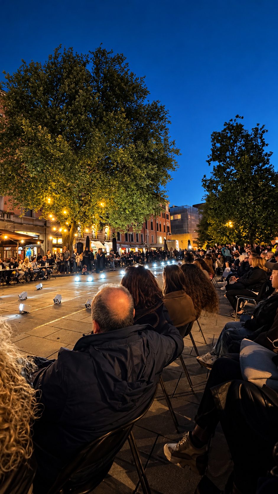 Piazza Mazzini al tramonto, con il pubblico seduto lungo la passerella illuminata da luci a terra